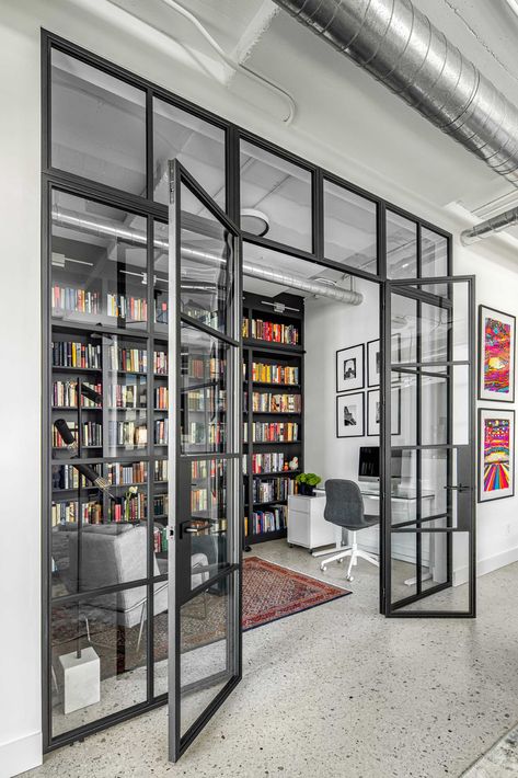 A modern home library enclosed behind a glass wall, has custom black shelving and a ladder to reach the upper shelves. Library And Office Room, Modern Library Design Home, Office Divider Ideas, Shared Office Space Ideas Home, Home Gallery Design, Library Design Home, Home Library Aesthetic, Industrial Office Space, Cinnamon Bites