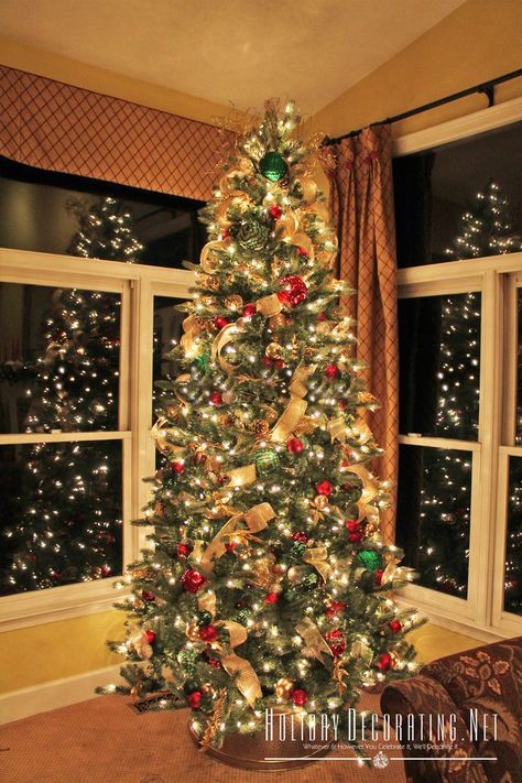 Traditional Christmas tree decorated in red, green and gold against a backdrop of corner windows. Gold Red And Green Christmas Tree, Red Green Gold Christmas Decor, Red Green And Gold Christmas Tree, Red Green Gold Christmas, Balcony Decor Ideas, Elegant Christmas Tree Decorations, Red Gold Christmas, Tall Christmas Trees, Tree Themes