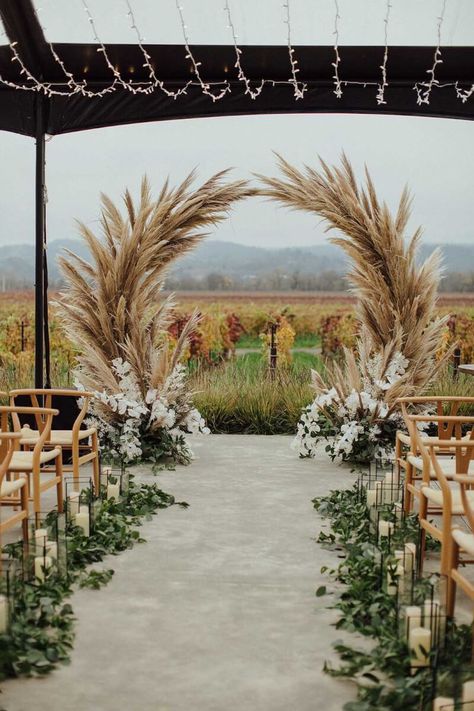 Looking down the aisle at the pampas grass wedding arch with the vineyard in the background. Wedding Ideas Pampas, Pampa Wedding Decor, Pampas Decor Wedding, Wedding Aisle Boho, Wedding Decorations Pampas, Country Wedding Arch, Unique Wedding Arch Ideas, Flower Wedding Aisle, Wedding Isles Decoration