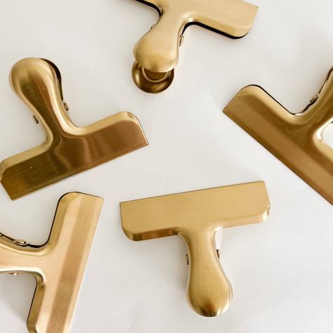 Brass clips. Stylish way to store things in office or pantry. Made of stainless steel with a brass finish. Sold individually. 3 across, 2.5 tall Brushed Brass Accessories, Brass Or Gold, Brass Accents Office, Office Clips, Brass Clips, Bag Of Chips, Chip Clips, Gold Kitchen, Room Planning