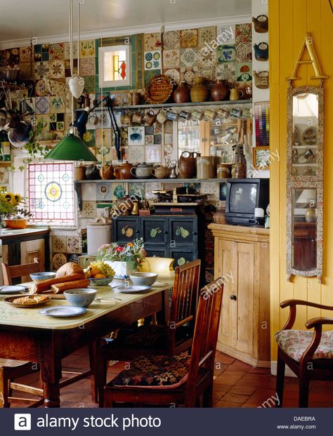 Download this stock image: Old pine table and chairs in cluttered cottage kitchen with narrow mirror on the wall - DAEBRA from Alamy's library of millions of high resolution stock photos, illustrations and vectors. Pine Table And Chairs, Narrow Mirror, Maximalist Kitchen, Boho Style Kitchen, Kitchen Clutter, Eclectic Kitchen, Pine Table, Mirror On The Wall, Maximalist Decor