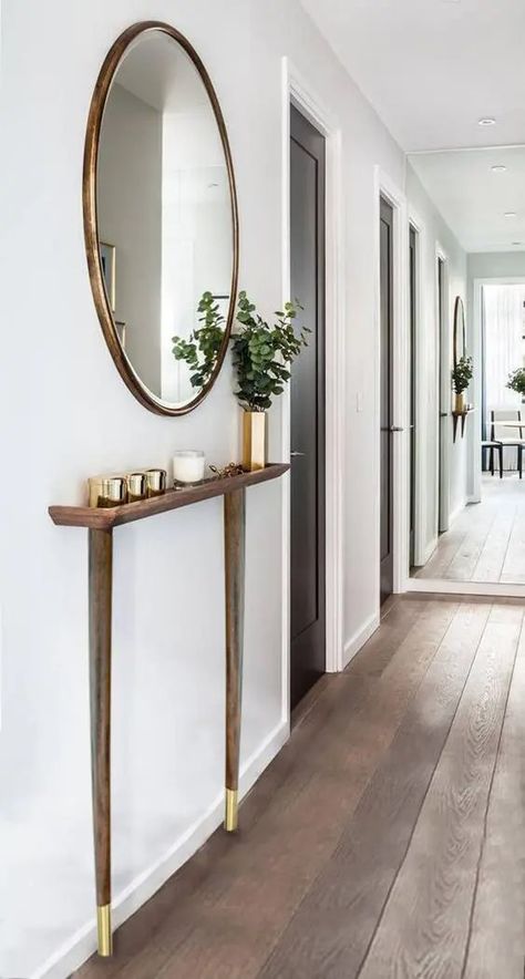 A contemporary entryway with a super sleek console with brass legs, brass jar candles and a vase, a round mirror in a brass frame is cool Decorating A Hallway, Sleek Console, Console Ideas, Contemporary Entryway, Jar Candles, Round Mirror, Brass Frame, Round Mirrors, Candle Jars