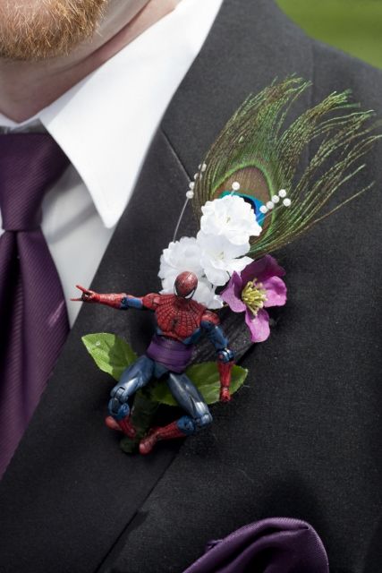 Handmade Action figure Boutonnieres with purple and white flowers and peacock feathers. This groomsman had spiderman. Super Hero Boutonniere, Nerdy Boutonniere, Music Boutonniere, Marvel Wedding Theme, Peacock Boutonniere Groomsmen, Spiderman Wedding, Peacock Feather Corsage, Mens Boutonniere, Body Flowers