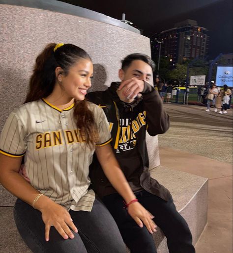 There is a couple of a guy and a girl sitting together at the Padres San Diego baseball game wearing matching brown and white Padres jerseys Pirates Baseball Game Outfit, Padres Outfit Women, Black Outfits Couples, Padres Game Outfit, San Diego Padres Outfit, Brown And Black Outfits, Baseball Game Pictures, Outfit Inspo Brown, Baseball Game Outfit