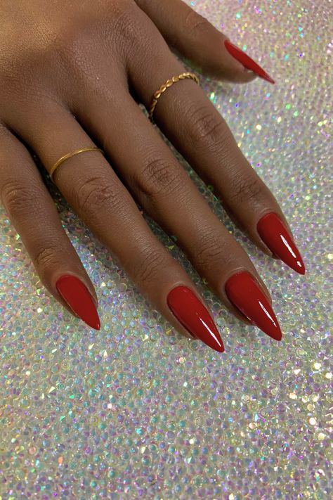 True red dip powder nails on dark brown skin on stiletto nail tips. Fall Red Nails Almond, Red Nails Stiletto Almond, Red Polish Nail Designs, Nail Colors 2023 Dip, Burgundy Dip Powder Nails, Red Claw Nails, Stiletto Nails Simple, Almond Nails Designs Red, Red 90s Nails