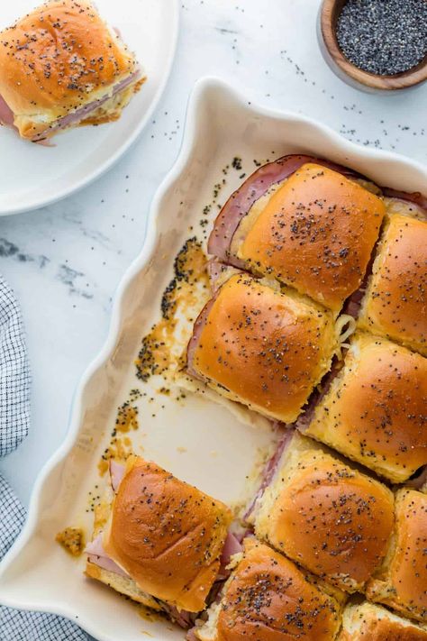 Funeral Sandwiches are delicious ham and cheese sliders you can make as an easy appetizer recipe or as a family friendly meal. Full of warm salty ham, nutty Swiss cheese and topped with a tangy Dijon butter sauce, these mini slider sandwiches are nothing to be sad about! Overnight Ham And Cheese Sliders, Ham Biscuits With Poppy Seeds, Sauce For Ham Sandwiches, Little Hammies Sandwiches, Mini Ham And Cheese Sliders, Turkey Ham Sliders, Hot Ham And Cheese Sandwiches Baked, Warm Sandwich Recipes, Ham And Cheese Melts