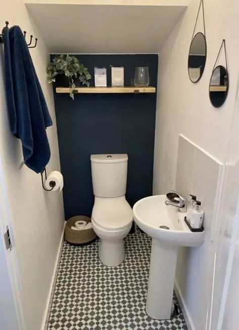 a small and cool under the stairs powder room with a navy accent wall, a printed floor, an open shelf with decor and a free standing sink looks stylish Understairs Toilet, Vogue Decor, Room Under Stairs, Wc Decoration, Tiny Powder Room, Small Downstairs Toilet, Cloakroom Toilet, Bathroom Under Stairs, Toilette Design