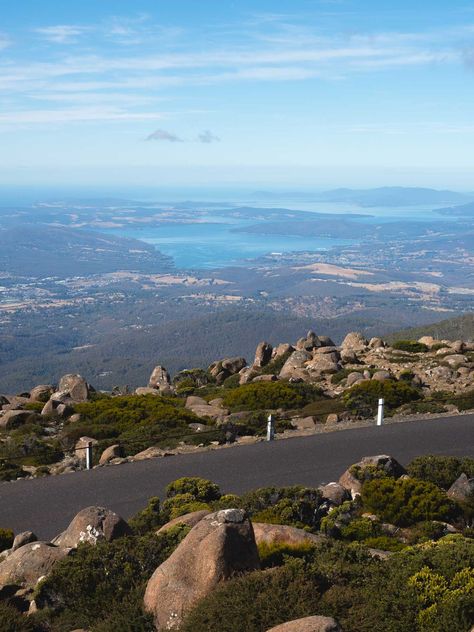 Breathtaking views over Hobart and surrounds from the top of Mount Wellington. See nearby rocks and greenery, then further away you will see the River Derwent and stunning blue water. Hobart Aesthetic, Hobart Tasmania Aesthetic, Tasmania Aesthetic, Hobart City, Fern Tree, Tasmania Travel, Hobart Tasmania, Silver Falls, Stunning Landscapes