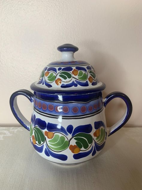 Brighten up your kitchen with this beautiful hand-painted Talavera pottery sugar bowl!  Featuring a vibrant floral design with a matching lid.  This beautiful ceramic piece bring a colorful piece of folk art into your home.  Whether used to store sugar, spices, or small trinkets, this handcrafted bowl is both functional and decorative.