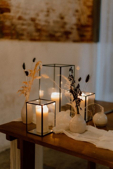 This features a op table at a barn wedding. The image focuses on a collection of differently sized black box lanterns and vases with dried flowers in them. Wicker Lanterns, Pond Wedding, Wedding Top Table, Black Lantern, Wedding Lanterns, Wedding Top, Top Table, Black Box, Modern Table