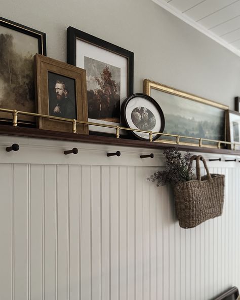 The DIY brass rail gallery wall deserves some still photos😍 I wish I could take credit for this idea, but Jeff was actually the one who brought it up! I’m so glad he did because it brings so much warmth and character to the space! And I have another place to display art 😂 Comment SHOP below to receive a DM with the link to shop this post on my LTK ⬇ https://liketk.it/4ShTY #mixerofstyles #interiordesign #hometakestime #transitionaldesign #mydomaine #wearevivir #mycrumbshome #bhghome #bhgst... Wall Shelf For Hallway, Gallery Wall Between Sconces, Hallway Photo Ledge, Rustic Picture Shelf, Tall Picture Frame Ideas, Picture Ledge Family Photos, Wainscoting Ideas With Shelf, Gallery Wall With Curtain Rod, Picture Frame Ledge Ideas