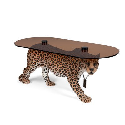 The Dope as Hell coffee table will make a resounding impression on your guests. The color-coated resin panther that is used to hold the tempered glass is innovative in its appeal and makes for an exotic decorative item in your interiors. This limited edition product is innovative in design and style, having only 1000 being made worldwide. Base Color: Brown | Bold Monkey Dope as Hell Figurine Pink Coffee Table in Brown | Wayfair Glam Coffee Table, Monkey Coffee, Monkey Style, Glamorous Interiors, Dutch Furniture, Tempered Glass Table Top, Jeff Koons, Unique Centerpieces, Trendy Living Rooms