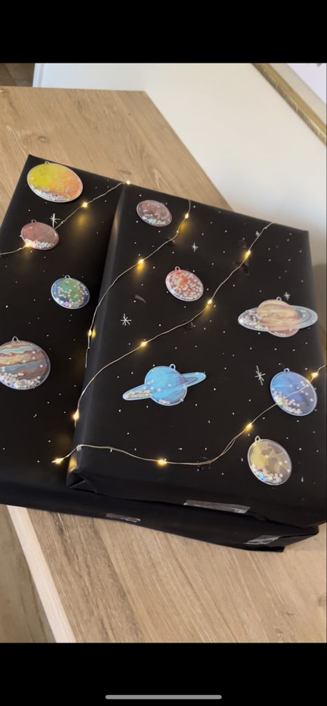 Black wrapping paper with white dots, planets and twinkle lights Space Theme Gift Wrapping, Space Gift Wrapping Ideas, Space Related Gifts, Black Wrapping Paper Ideas Birthday, Diy Space Gifts, Space Gifts For Men, Baby Boy Gift Wrapping Ideas, Birthday Wrapping Ideas For Men, Gift Raping