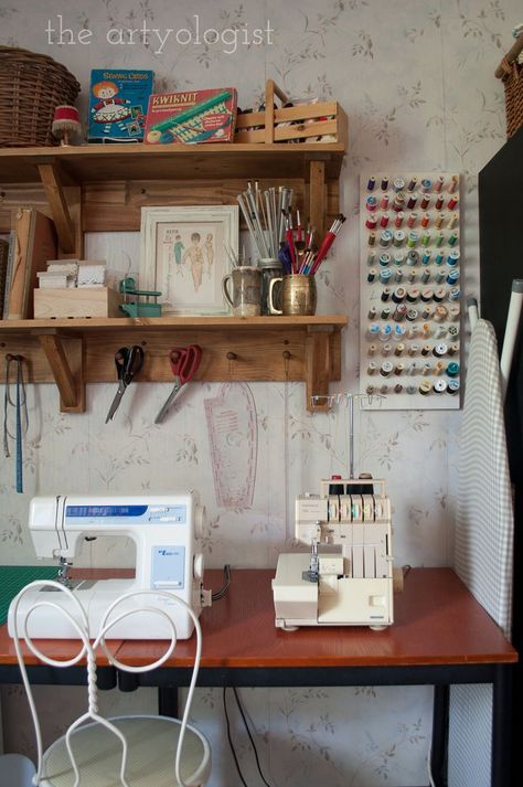 A desk sits against a wall with a sewing machine and serger on top of it. Two wall shelves are hung above with baskets of supplies and vintage sewing patterns and supplies displayed on them. Floating Shelves Sewing Room, Sewing Wall Storage, Farmhouse Sewing Room Ideas, Sewing Setup Small Space, Vintage Sewing Desk, Sewing Room Vintage, Sewing Room Organisation, Cottage Sewing Room, Cozy Sewing Room