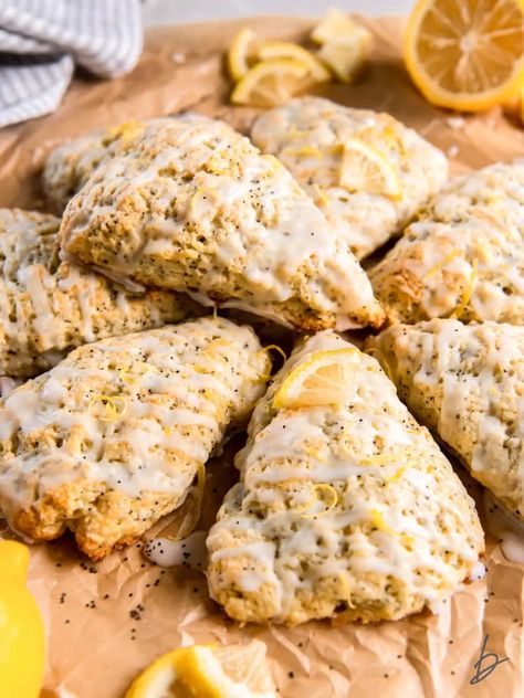 lemon poppyseed scone with glaze on top of more scones on parchment paper. Lemon Poppyseed Scones, Orange Poppyseed Scones, Lemon Poppyseed Scones Recipe, Lemon Poppy Seed Sourdough Muffins, Scones Lemon Poppyseed, Lemon And Poppy Seed Muffins, Buttermilk Drop Biscuits, Lemon Poppy Seed Scones, Mini Scones