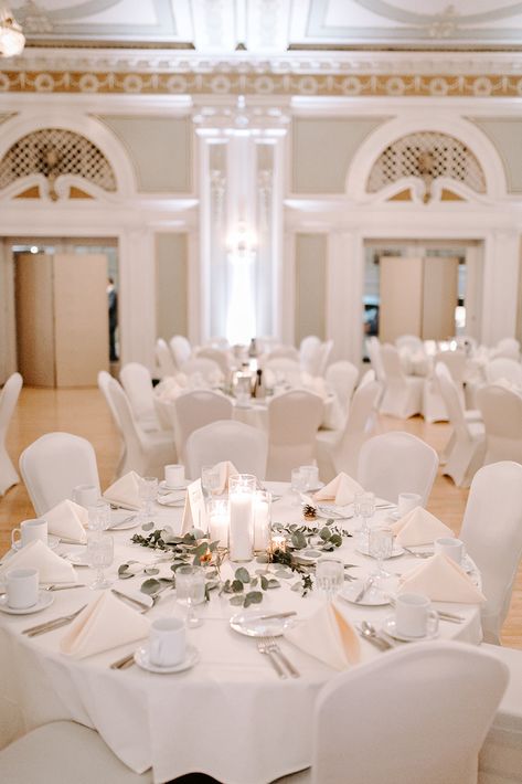 In a venue like Greysolon Ballroom in Duluth, MN, you don't need much decor to finish the look. Cait & Zach's minimalist classic white wedding put the focus on the people and spending time together while adding decor in specific areas to make an impact. Their copper wedding arch and white chair covers made all the difference in this vintage ballroom.  Décor: The Vault Planning: Northland Special Events Florals: Superior Blooms Photography: Kate Becker Venue: Greysolon Ballroom Wedding White Chair Covers, Wedding With Chair Covers, White Covered Chairs Wedding, White Chair Covers Wedding Receptions, Ballroom Table Setting, White Table And Chairs Wedding, Ballroom Wedding Decoration Simple, Greysolon Ballroom Wedding, Covered Chairs Wedding