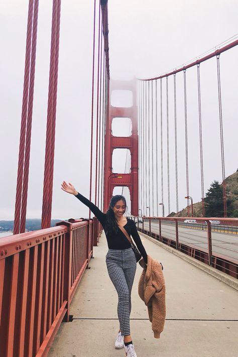 Girl is smiling on the Golden Gate Bridge with arms held wide open. She has a long black hair tied into a ponytail, long black sleeve v neck shirt, and black and white plaid pants. She’s showing how to dress chic and casual in San francisco. Golden Gate Bridge Picture Ideas, School Outfits For College, Plaid Pants Outfit, Glass Bridge, Bridge Pose, Vacation Inspiration, City Outfits, Pic Pose, Vacation Photos