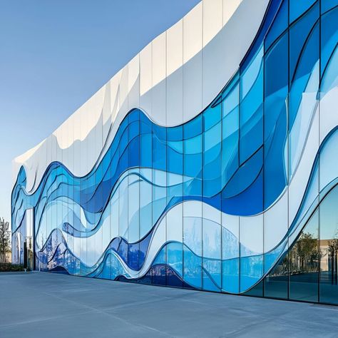 A modern building facade showcases ceramic glass with flowing, wave-like patterns in varied blue hues, mimicking the movement of water. The glass installation creates a dynamic visual effect that stands out against white and transparent sections, enhancing the building’s sleek aesthetic. The undulating shapes and gradient blues give an illusion of ocean waves, capturing light to add depth and movement, making it a unique urban material building design. Wave Facade Architecture, Wave Design Architecture, Water Facade Architecture, Blue Facade Architecture, Architecture Inspired By Water, Water Museum Architecture, Blue Hues Aesthetic, Terminal Design Architecture, Blue Architecture Aesthetic