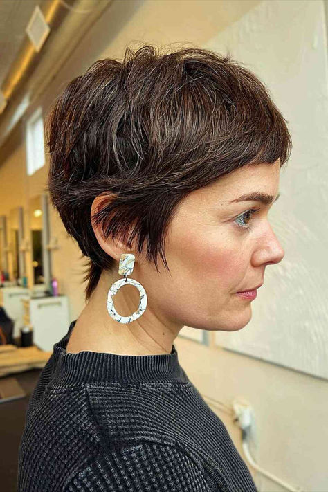 Thick brunette pixie cut with mini bangs, a modern twist on a 90s classic. Pixie Short Bangs Haircut, Growing Out Pixie With Bangs, Pixie Haircut Women In 40s, Chic Short Haircuts For Thick Hair, Thick Straight Short Hair, Long Pixie Updo, "shixie" Haircut, Winter Pixie Haircut, Pixie Before And After