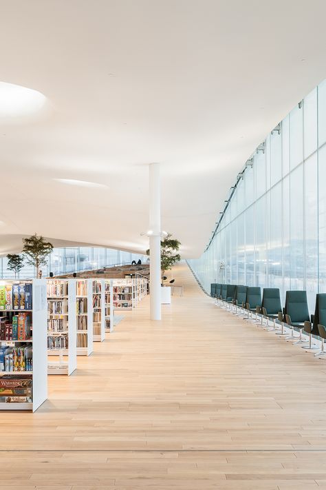 Modern library with light coloured wood floors, large floor to ceiling windows, a curved ceiling and large decorative plants Oodi Library Helsinki, Helsinki Central Library, Central Library, Suspended Ceiling, Meeting Place, Library Design, Materials And Textures, Three Floor, Design Solutions