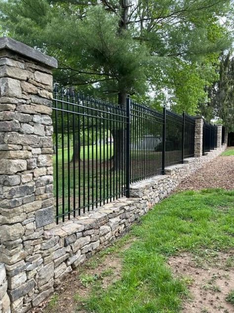 Adding our iron fencing with this beautiful rock wall and pillars elevates the elegance of this already stunning property.   Upgrade your outdoor space with our durable and stylish iron fencing options. Contact us now to find the perfect fit for your property.  #IronFenceShop #ironfence #ironfencing #elegant #curbappeal #rockwall #fencing #backyard Fence Wrought Iron, Fenced In House, Rock And Wood Fence, Stone And Iron Fence Ideas, Fencing For Large Property, Farm Fences And Gates, Hillside Fence, Cottage Fence Ideas, Stone Fence Ideas