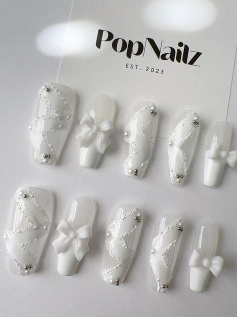 Welcome to PopNailz, your premier destination for high-quality handmade press-on nails that blend elegance and convenience. Our Elegant White Lace and Bow Press-On Nails are meticulously crafted to offer you a salon-quality manicure from the comfort of your home. Product Features: Handmade Excellence: Each nail is carefully hand-painted and adorned with delicate lace patterns and charming bow accents, ensuring a unique, high-quality product. Reusable & Durable: Designed for multiple uses, our pr Nail Art Designs White Nails, Cute White Long Nails, Cute Nail Designs White, Nail Salon Pictures, White Nails With Bow, White Korean Nails, White Elegant Nails, White Nails With Charms, Nail Art Designs White