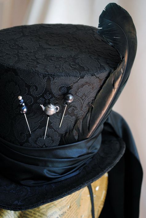 "A total black Mad Hatter ladies top hat to match the darkest Alice in Wonderland inspired costumes! This glorious hat is covered with a wonderful black brocade fabric. It is embellished with a long black taffeta train that goes around the brim and falls luxuriously at the back. The hat wouldn't be complete without some \"mad hatter\" details! A black duck feather, three unique hat pins and the signature 10/6 tag! Cause around here it's always tea-time! Fully lined with satin. Attaches with a th How To Make Mad Hatter Hat, Gothic Top Hat, Top Hat Character Design, Top Hat Aesthetic, Mad Hatter Inspired Outfit, Gothic Mad Hatter, Mad Hatter Costume Female, Mad Hatter Outfit, Wedding Top Hat