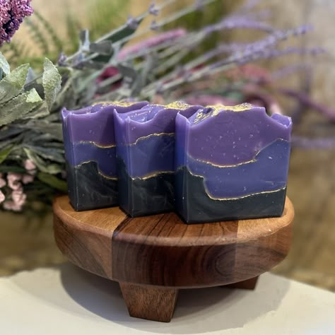 Introducing our luxurious vegan artisan soap bar, Regal! Handcrafted with utmost care, this stunning soap bar showcases captivating hues of black, purples, and gold, reminiscent of royalty. Infused with a delightful violet fragrance, each lather creates a sensorial experience that transports you to a tranquil garden blooming with sweet violets. With its ethically sourced ingredients and elegant design, Regal is the perfect addition to your pampering routine, offering a touch of opulence and a bu Soap Making Aesthetic, Bar Soap Aesthetic, Bar Soap Recipes, Soap Bar Design, Witchy Soap, Artisan Soap Packaging, Soap Accessories, Royalty Soaps, Purple Bar