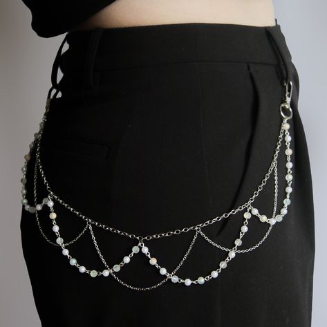 Introducing the beaded belt chain, a must-have accessory to elevate your wardrobe effortlessly. Crafted with meticulous attention to detail, this chain features a stunning layering of silver chains intertwined with delicate beaded strands. The beaded chains, adorned with lustrous pearls and clear rainbow beads, exude timeless elegance and versatility, seamlessly complementing any outfit, regardless of its colour or pattern. Instantly transform your look with a touch of sophistication and charm as this chain effortlessly adds style, interest, and beauty to any ensemble. Whether paired with pants or skirts, this accessory is the perfect finishing touch to showcase your unique sense of fashion.  specifications: Length is 52 cm  (DM me if you need a shorter or longer length) Stainless Steel Lo Strings Of Beads, Spider Web Body Chain, Chain Accessories Fashion, Pearl Chain Belt, Diy Pant Chain, Clothes With Chains, Bead Belt Chain, Diy Waist Chain, Beads Outfit