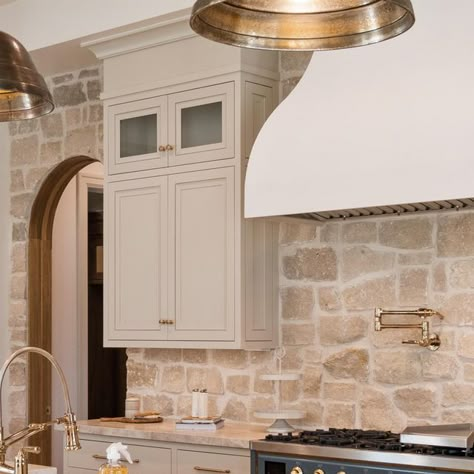 Davies Design Build on Instagram: "The kitchen in our 2023 @uvparade home was a fan favorite! We loved taking our clients vision and bringing it to life. Here are the details! -The stone we used is from @beehivebrickandstone and we used the Bonneville stone with white grout. -The cabinet color is SW Accessible Beige. #kitchendesign #cabinetdesign #designbuild #sketchup #utahbuilder #utahcustomhomebuilder #constructbuild #buildersofig #luxedesign #beautifulhome #interiorarchitecture #luxehome #dreamhome #utah #designbuild #construction #constructionlife #stone #realestate #design #interiordesign #finishcarpentry #lightingdesign #kitchenbacksplash #kitcheninspiration #kitchen" Stone Range Hood Kitchen, Stonework In Kitchen, Limestone Tile Backsplash, Kitchen Stone Wall Ideas, Tan Stone Backsplash Kitchen, Cottage Kitchen Stone Wall, White Cabinets Stone Backsplash, Rough Stone Backsplash Kitchen, Stone Wall Backsplash