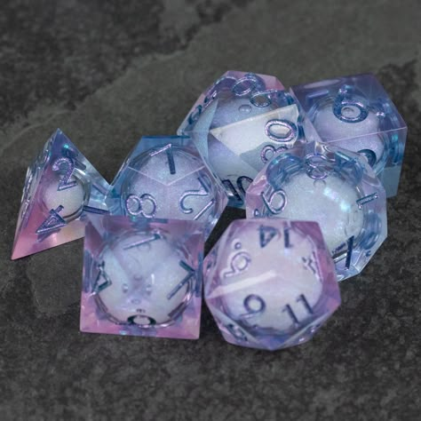 Fae magic was as difficult to understand as the Fae themselves. It seemed to exist by its own rules.Beautiful, clear pink and light blue dice with a shimmering liquid core inside. The dice shimmer magically when shaken. Note that while the pictures are unedited, the color really pops because of the dark background. You'll probably find them less vibrant in normal light.Each set contains the standard 7 roleplaying dice - d4, d6, d8 d10, d10 in 10's, d12, and the classic d20.Please keep in mind th Liquid Core Dice, Dnd Dice Aesthetic, Dice Inspiration, Dice Aesthetic, Fae Magic, Dice Art, Cool Dnd Dice, Pretty Dice, Dice Dragon