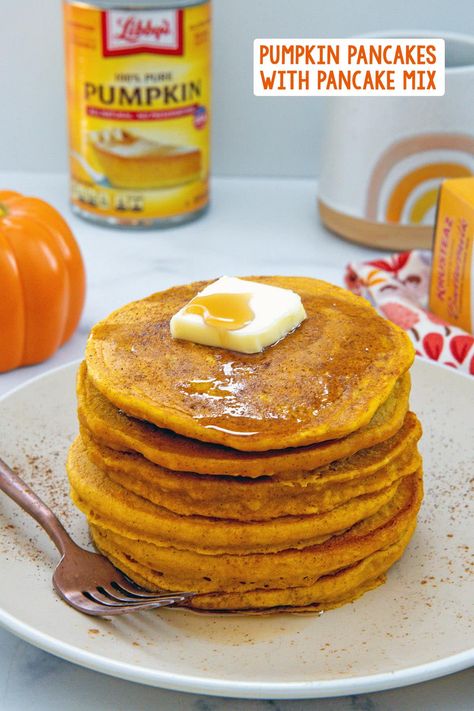 Head on view of a stack of pumpkin pancakes topped with a pat of butter with pumpkin, can of pumpkin puree, mug, and box of pancake mix in background and recipe title at top. Pumpkin Pancakes With Krusteaz, Pumpkin Pancakes With Pancake Mix Recipe, Pumpkin Pancakes With Mix Easy, Boxed Pancake Mix Recipe, Pumpkin Buttermilk Pancakes, Pumpkin Oatmeal Pancakes, Pumpkin Pancakes Recipe, Pumpkin Pie Pancakes, Fluffy Pumpkin Pancakes