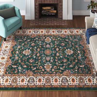 This area rug grounds your living room with a design inspired by traditional Oriental rug patterns. It's power-loomed from polyester, and it has a floral print in green, orange, and brown hues. Its material has excellent resistance to mildew and aging. We love how the 0.5" pile height makes it an ideal pick for adding a plush stage setter to your living room or bedroom. Best of all, this rug is stain-resistant, so it's ready to handle regular use. We recommend pairing it with a rug pad to preven Bold Living Room Rug, Jewel Tone Rugs Living Rooms, Cottage Core Living Room Rugs, Green Orange Rug, Terracotta Rug Bedroom, Green And Blue Rugs, Wayfair Rugs Living Rooms, Green Rug Bedroom Aesthetic, Orange And Green Home Decor