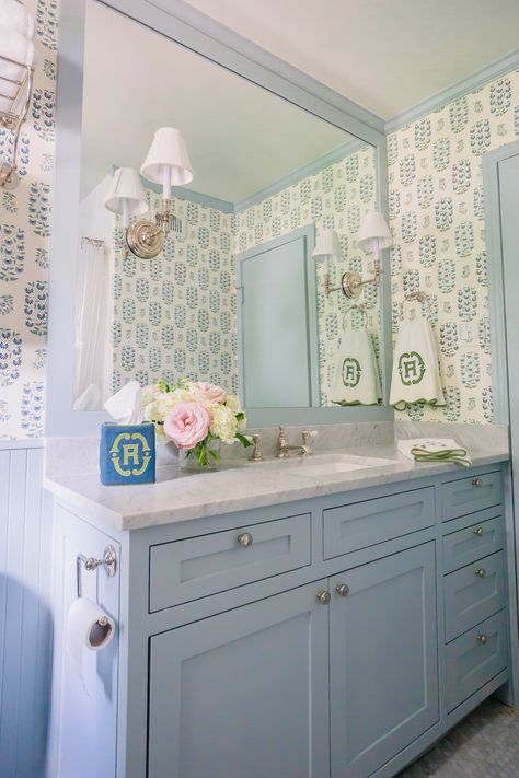 Blue trim, wallpaper, big mirror, sciences mounted in mirror, single sink, vanity cabinet layout, marble hex tile, wainscoting Blue Wallpaper Bath, Blue Vanity With Wallpaper, Blue Trim Bathroom, Grand Millenial Bathrooms, Navy Wallpaper Bathroom, Trim Around Mirror, Grand Millennial Bathroom, Blue Trim Interior, Tile Wainscoting