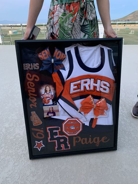 Senior Cheer Boxes Ideas, Framed Cheer Uniform, Senior Cheer Shadow Box Ideas, Cheerleader Shadow Box Ideas, Cheer Shout Out Ideas, Cheer Camp Crafts For Kids, Cheer Wall Ideas, Senior Night Baskets Cheer, Cheer Team Themes