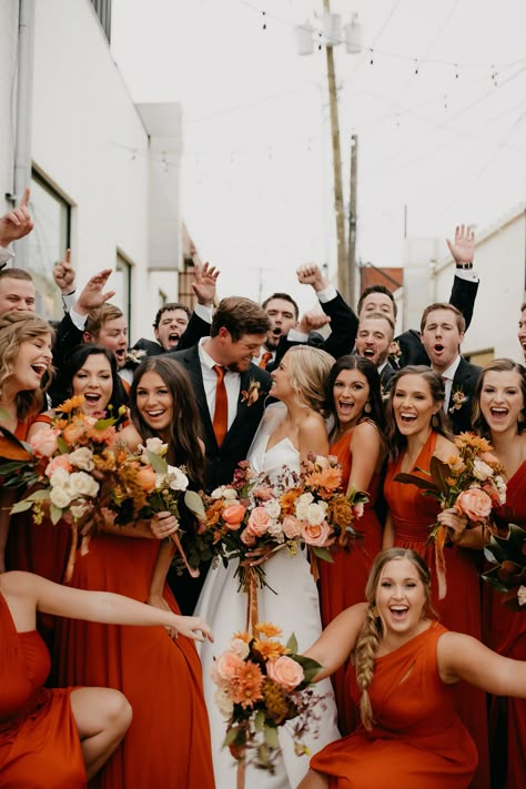 Bridesmaids and groomsmen cheering and celebrating around bride and groom wearing burnt orange bridesmaid dresses. Red Bridesmaid Dresses Fall, Color Combos 2023, Deep Red Bridesmaid Dresses, Fall Wedding Colors October, Burnt Orange Bridesmaid, Orange Flower Crown, October Wedding Colors, Grey Wedding Decor, Burnt Orange Bridesmaid Dresses