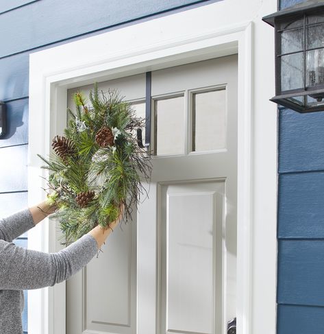 Hanging an evergreen wreath on a gray front door Wreath On Door, Double Door Wreath, Double Wreath, Hanging Wreaths, Wreath Hook, Double Door Wreaths, Outdoor Wreath, Moss Wreath, Valentine's Day Wreath