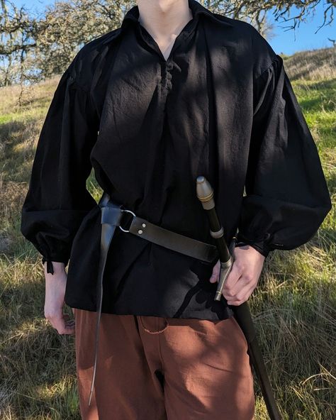 This medieval pirate shirt is the perfect piece for the full adventurer's look! Made with premium fine cotton, this shirt is super lightweight and breathable, making it easy to wear, no matter the weather. Made with big sleeves and a comfortable collar, no matter how you move in the shirt, whether that is fighting off bandits, receiving an award from a damsel, or scaling the Cliffs of Insanity, this shirt will move with you. The interior seams of the shirt are hemmed to prevent fray and the sleeves are fastened with ties around the wrists for an adjustable fit. - 100% premium durable cotton - Lightweight and easy to wear - Black and white colors - Handmade on the central coast of California, USA *Model is 6'3", and is wearing a size M* Medieval Clothing Men, Medieval Pirate, Medieval Shirt, Pirate Garb, Pirate Shirt, Medieval Clothes, Blouse Man, Big Sleeves, Pirate Shirts