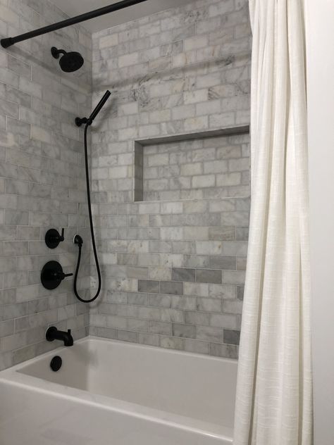 Farmhouse Shower Bathtub Combo - Matte Black Delta Fixtures with Floor and Decor Casa Antica Ocean Honed Marble Tile Redo Bathtub Shower Combo, Bathtub With Black Fixtures, Extra Long Tub Shower Combo, Tub Shower Combo Remodel Farmhouse, White Tub Black Fixtures, Bathroom Ideas Bathtub Shower Combo, Farmhouse Bathroom Bathtub Shower Combo, Shower Tile Ideas With Black Fixtures, Tiling Around Bathtub Tub Surround