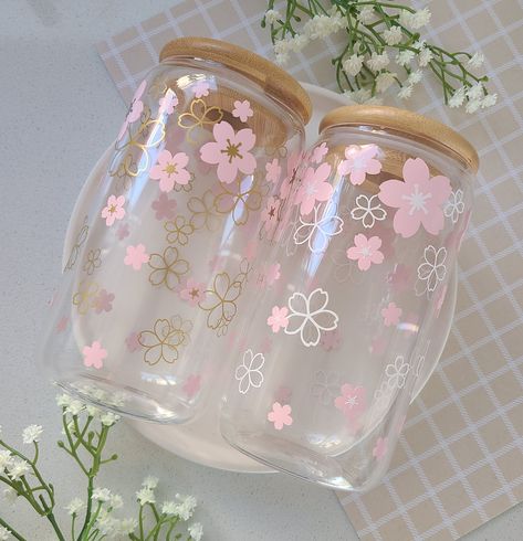 Cherry blossom season is such a beautiful time of the year, but unfortunately, it never lasts long. However, if you get this beautiful Sakura cup, it'll feel like it's all year round! Enjoy your daily coffee/tea in this simple & adorable glass cup! Our 16oz glass cups are great for your friends, significant other, family members, or just for yourself! The glass is durable and able to withstand both cold and hot beverages. The design is made with permanent vinyl and heat sealed to prolong the durability and life of the vinyl.  Order includes: 16oz glass cup, silicone sealed bamboo lid, and glass straw Cute Cups Designs, Cute Glass Cups, Cup Vinyl, Glass Tumbler Design, Kawaii Cups, Crockery Design, Painting Glass Jars, Blossom Season, Cute Coffee Cups