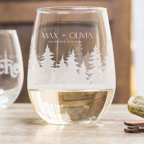 "PERSONALIZED WOODS STEMLESS WINE GLASSES These personalized and etched stemless wine glasses come with a beautiful design featuring an array of forrest trees that wrap around the glass. The design is personalized with names and a date. These are perfect for a forest-themed wedding! They can be gifts for the wedding party, wedding favors, toasting glasses, or a beautiful way to display specialty cocktails! Each order comes with 1 glass. 🤩 CUSTOM DESIGN 🤩 Want to add anything extra, change the Mountain Destination Wedding Favors, Wedding Etched Glass Ideas, Woodland Fairy Wedding, Mountain Themed Wedding, Outdoor Wedding Favors, Specialty Cocktails, Etched Wine Glasses, Wedding Wine Glasses, Toasting Glasses