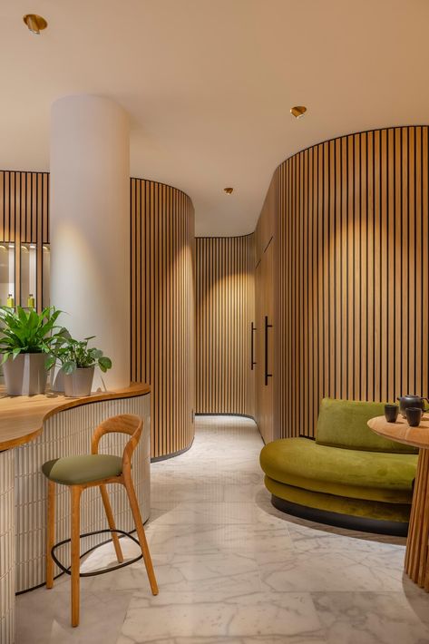 Blending into the organically shaped walls are the doors to the massage rooms, only noticeable by the black hardware. Curved Walls Interior, Tambour Wall, Rock Pigeon, Cannes 2024, Concealed Door, Organic Interior, Spa Interior Design, Concrete Interiors, Wood Walls