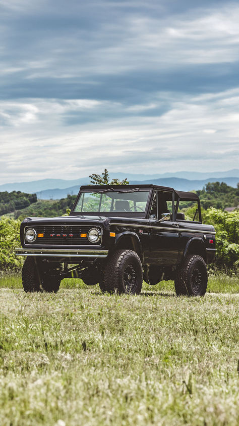 A classic black Ford Bronco with a soft top, set against a pastoral landscape with rolling hills and a soft cloudy sky in the background. Vintage Bronco Aesthetic, Ford Bronco Wallpaper Iphone, Black Ford Bronco, Ford Aesthetic, Ford Bronco Vintage, Vintage Broncos, Old Ford Bronco, Vintage Bronco, Broncos Pictures