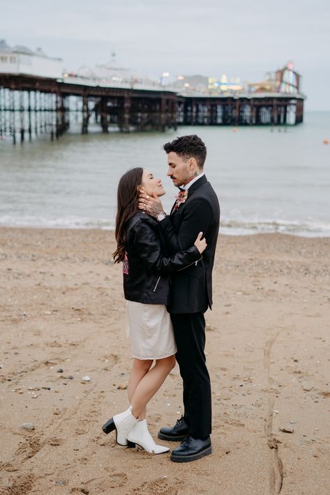 bride and groom on brighton beach with brighton pier in the background for their wedding photos after getting married at brighton town hall, bride is wearing a short wedding dress with white boots and a leather jacket, groom is wearing a black suit Brighton Wedding, Office Doors, Elopement Shoot, Paper Confetti, Beach Wedding Photography, Beach Wedding Photos, Brighton Beach, Town Hall, Brighton