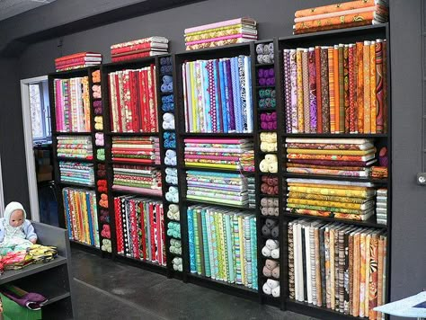 Black bookshelves for quilt shop bolt display Fabric Bolt Shelf, Quilt Shop Displays, Fabric Shop Display, Fabric Store Displays, Fabric Store Design, Thread Rack, Sewing Room Storage, Retail Store Interior Design, Clothing Store Interior