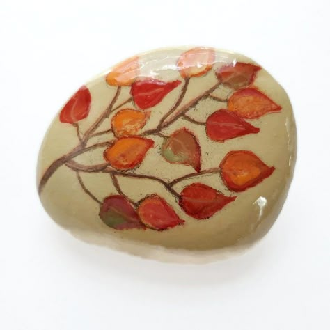 This is a painted rock with a tree branch of changing fall leaves, with the colors of green, yellow, orange and red, on brown branches. Share this rock as a kindness rock or use as a paper weight,  home decoration item. or teacher gift. Painted Rocks For Fall, Rock Painting Ideas Fall, Autumn Rock Painting Ideas, Rock Decorating Ideas, Thanksgiving Painted Rocks, Fall Painted Rocks, Fall Rock Painting Ideas, Fall Rock Painting, Thanksgiving Rocks