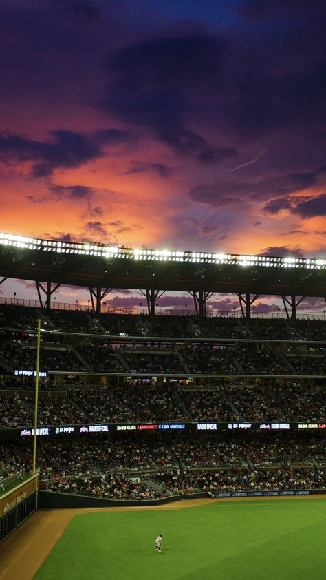 An orangey purple sunset is the backdrop of a full-capacity Truist Park. Baseball Wallpaper Aesthetic, Truist Park Atlanta, Baseball Phone Wallpaper, Wallpaper Backgrounds Baseball, Baseball Field Aesthetic, Atlanta Braves Iphone Wallpaper, Funny Thanksgiving Pictures, Softball Aesthetic, Savannah Bananas