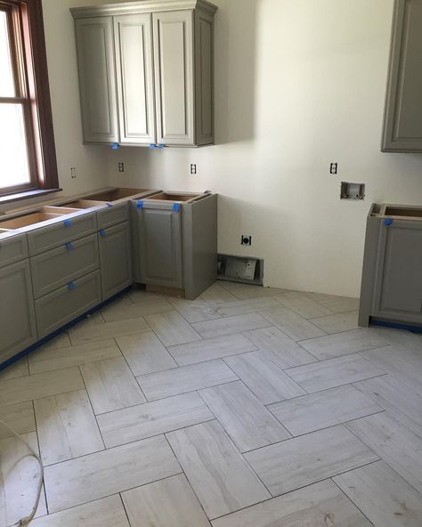 Love this herringbone tile pattern in this amazing laundry room that's in the works! Wood Floors With Tile Transition, Big Herringbone Tile Floor, 12x24 Tile Herringbone Pattern, Large Tile Herringbone Floor, Engineered Tile Flooring, Farmhouse Kitchen With Tile Floor, Large Herringbone Tile Floor Kitchen, Laundry Room Herringbone Tile Floor, Herringbone Tile Floor Laundry Room