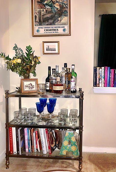 This shelf-style bar cart is multi-purpose, serving as both display for my better barware and storage for my growing cook book collection. Bar Cart With Books, Cocktail Glass Storage, Bar Cart Bookshelf, Bar Shelf Styling, Glass Shelf Decor, Chic Bar Cart, Bar Cart Aesthetic, Alcohol Display, Bookshelf Bar