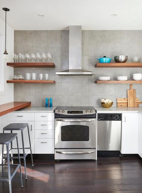 White and gray contemporary kitchen boasts wood floating shelves mounted to gray grid backsplash tiles on either side of a stainless steel hood fixed above a stainless steel oven range. Kitchen Hood Floating Shelves, Floating Shelves On Either Side Of Range Hood, Open Shelving On Either Side Of Range Hood, Contemporary Range Hood Ideas, Floating Shelves Next To Oven Hood, Floating Shelves Range Hood, Small Kitchen Range Hood, Range Hood Floating Shelves, Open Shelves Above Stove